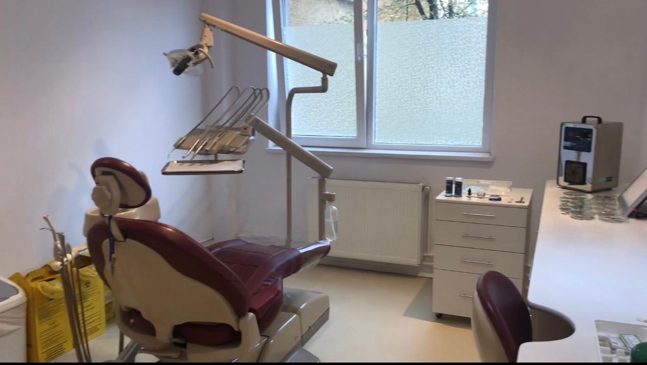 Sala de tratament Medical Dent, cu scaun stomatologic vișiniu și lampă dentară